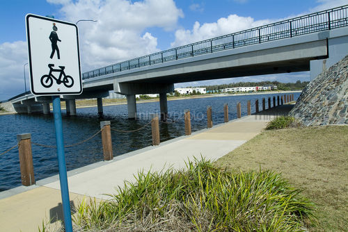Road bridge over lake in residential community with bike track sign in foreground - Mining Photo Stock Library