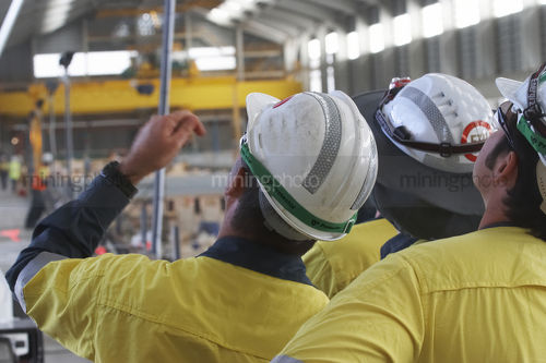 Group of mine construction workers in full PPE discussing the task at hand. - Mining Photo Stock Library