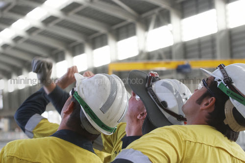 Mine construction workers in full PPE observing construction work inside building plant. - Mining Photo Stock Library