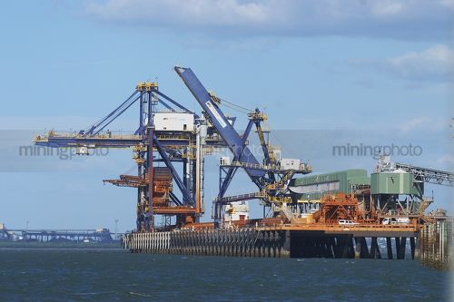 Ship loader at coal wharf.  great full sun photo with colour.  coal stockpiles in the distance. - Mining Photo Stock Library