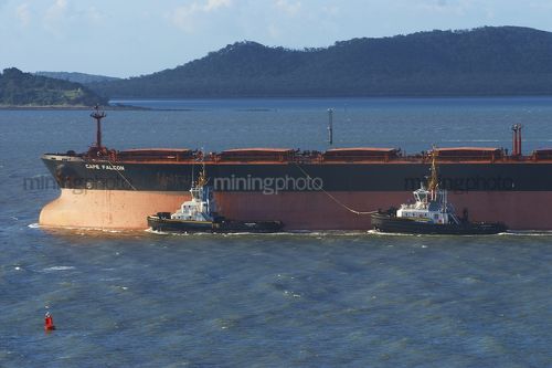 Two tugboats escort ship through shipping lane into port. - Mining Photo Stock Library