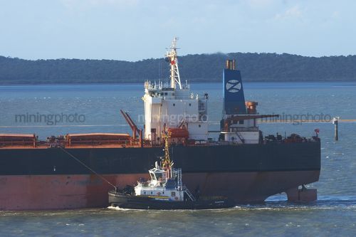 Tugboat escort ship through shipping lane into port. - Mining Photo Stock Library