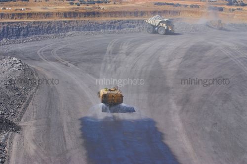 Water cart spraying water on road in haul truck dump turnaround area.  dust suppression. - Mining Photo Stock Library