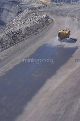 Water cart spraying water on haul access road in open cut mine.  aerial photo. - Mining Photo Stock Library