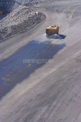 Water cart spraying water on haul access road in open cut mine.  aerial photo. - Mining Photo Stock Library
