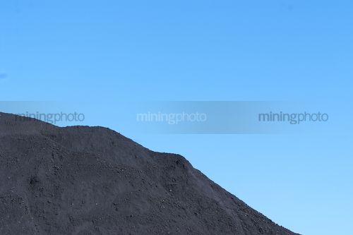 Generic close up shot of a coal stock pile.  blue sky in the background. - Mining Photo Stock Library