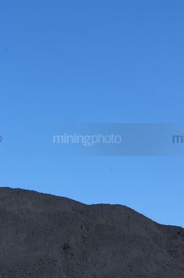 Generic close up shot of a coal stock pile.  blue sky in the background. - Mining Photo Stock Library