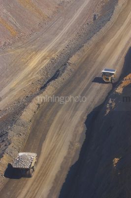 Two haul trucks on haul access road in open cut mine site.  aerial vertical photo. - Mining Photo Stock Library