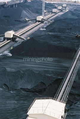 Stockpiled coal at port facility with heavy rail and coal loaders - Mining Photo Stock Library