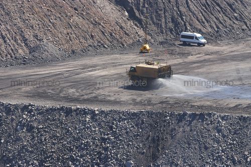 Water cart spraying water as dust suppression in open cut coal mine site. - Mining Photo Stock Library