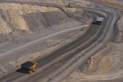 Loaded haul truck with coal following haul truck with overburden in open cut coal mine.  aerial shot. - Mining Photo Stock Library