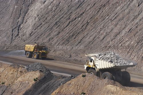 Loaded haul trcuk passes water cart spraying for dust suppression in open cut coal mine.  bowen basin Queensland. - Mining Photo Stock Library