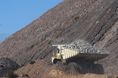 Close up photo of loaded haul truck in open cut coal mine.  blue sky behind. - Mining Photo Stock Library