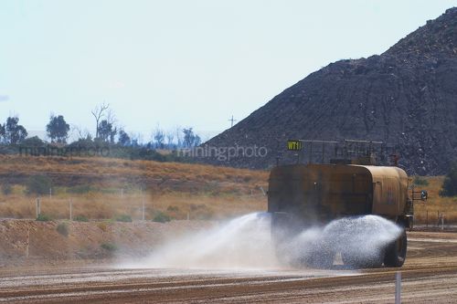Water cart spraying water on haul road in a mine. - Mining Photo Stock Library