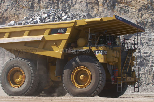 Close up photo of yellow haul truck in open cut coal mine. - Mining Photo Stock Library