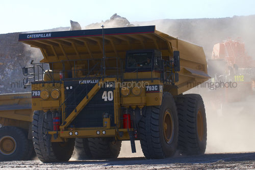 Haul truck loaded with overburden shot head on with excavator in background.  open cut coal mine. - Mining Photo Stock Library
