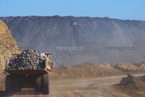 Haul truck loaded with overburden driving along access road in open cut coal mine.  plenty of space on RHS for copy, great 2 page spread shot. - Mining Photo Stock Library