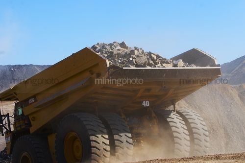 Loaded haul truck driving down access ramp in open cut coal mine.  shot from behind to show rear of truck. - Mining Photo Stock Library