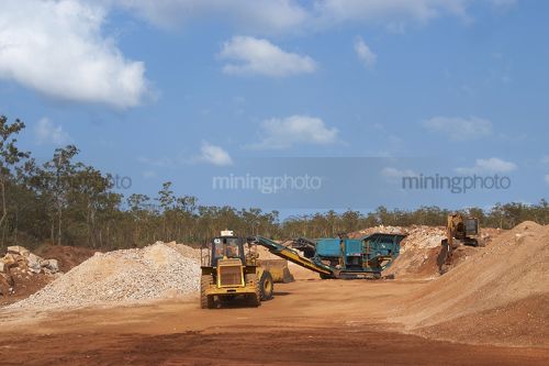 Loader working with portable crusher and excavator in a quarry in a mine site.   - Mining Photo Stock Library