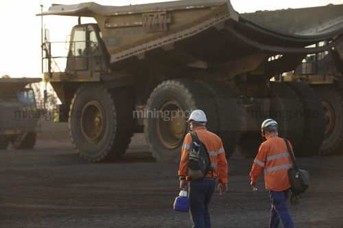 Haul truck drivers with their backpacks walking at the begining of the shift to their trucks at the go line. - Mining Photo Stock Library