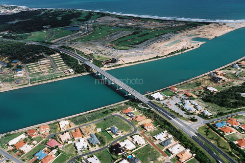 Aerial of highway bridge over river near ocean property subdivision  - Mining Photo Stock Library