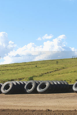 Truck tyre stock pile on mine site with green revegetation in the background.  vertical image. - Mining Photo Stock Library