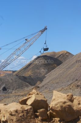 Bucket of a dragline with deep blue sky behind.  shot from rock level at the ground.  portrait image. - Mining Photo Stock Library