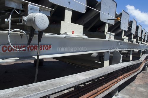 Close up photo of the side of an overland conveyor.  conveyor stop safety sign clearly visible. - Mining Photo Stock Library