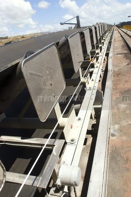 Vertical photo of an overland coal conveyor at a coal terminal. reclaimers in the background. - Mining Photo Stock Library