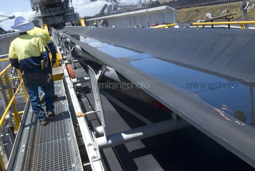 Two 2 mine workers on walkway adjacent to a coal conveyor in a coal terminal. - Mining Photo Stock Library