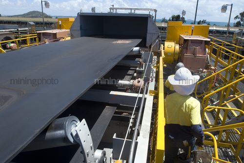Two 2 mine workers on walkway adjacent to a coal conveyor at a coal terminal. - Mining Photo Stock Library