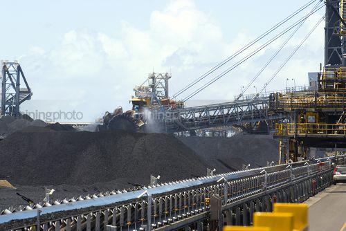 Close up photo of coal reclaimers working large stockpiles at coal shipping terminal. - Mining Photo Stock Library