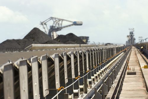 Dramatic shot looking along conveyor to reclaimers and stockpiles at a coal terminal.  selective focus with foreground in focus. - Mining Photo Stock Library