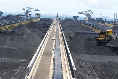Wide aerial shot of a coal terminal.  Reclaimers working coal stockpiles.  light vehicles on access road give scale. - Mining Photo Stock Library