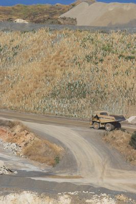Haul truck on access road passing by rehab and revegation planting work. - Mining Photo Stock Library