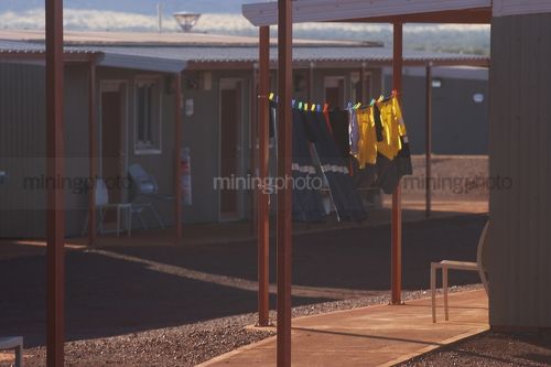 Workers PPE shirts hanging on washing line in front of mine camp accomodation. - Mining Photo Stock Library