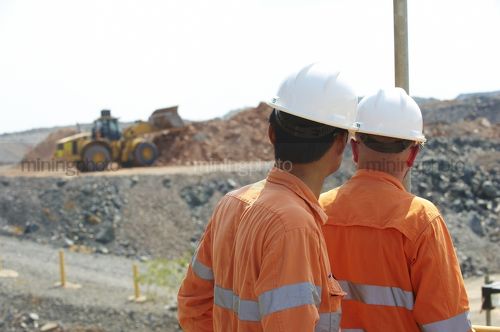 Workers in full PPE watching loader stockpiling product at mine site. - Mining Photo Stock Library