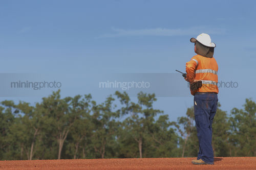 Mine site supervisor in full PPE with radio communications at mining site. - Mining Photo Stock Library