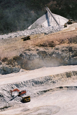 Aerial photo of haul trucks being loaded in open cut mine site.  product stockpile in background. - Mining Photo Stock Library