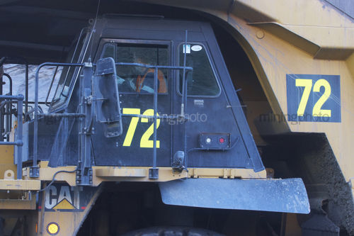 Close up photo of haul truck mine site driver driving in open cut mining pit. - Mining Photo Stock Library