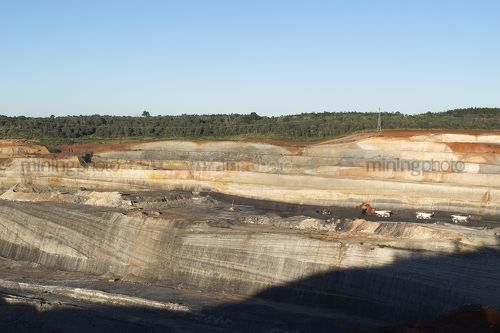 Wide photo of open cut coal mine.  digger, haul trucks and machinery in operation.  high walls and coal seam. - Mining Photo Stock Library