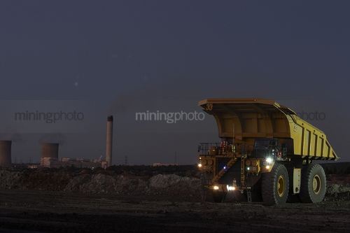 Dusk photo of haul truck unloading overburden in open cut coal mine.  power station in background. - Mining Photo Stock Library