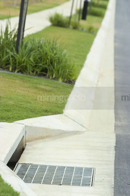Storm water drain with landscaped subdivision footpath in background  - Mining Photo Stock Library