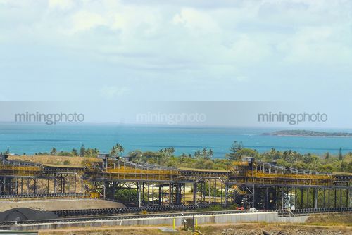 Wide photo of coal stockpiles at shipping coal terminal.  overhead conveyors clearly seen. - Mining Photo Stock Library