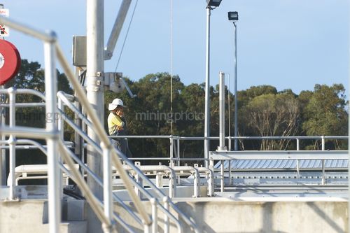 Worker in full PPE communicating on a radio.  water treatment plant. - Mining Photo Stock Library