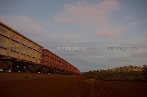 Iron ore train moving through the Pilbarra at dawn. generic photo of heavy rail. - Mining Photo Stock Library