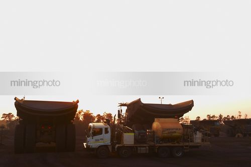 Mine site service truck with haul trucks at the go line. shot at dawn. - Mining Photo Stock Library