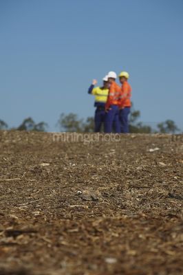 Three mine site workers in full PPE in discussion.  workers out of focus.  vertical shot. - Mining Photo Stock Library