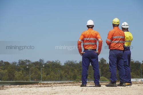 Three mine site workers in full PPE in discussion.  great generic photo for double page spread with room for copy. - Mining Photo Stock Library