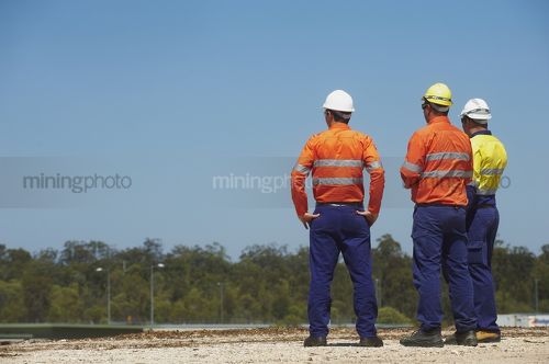 Three mine site workers in full PPE in discussion.  great generic photo for double page spread with room for copy. - Mining Photo Stock Library